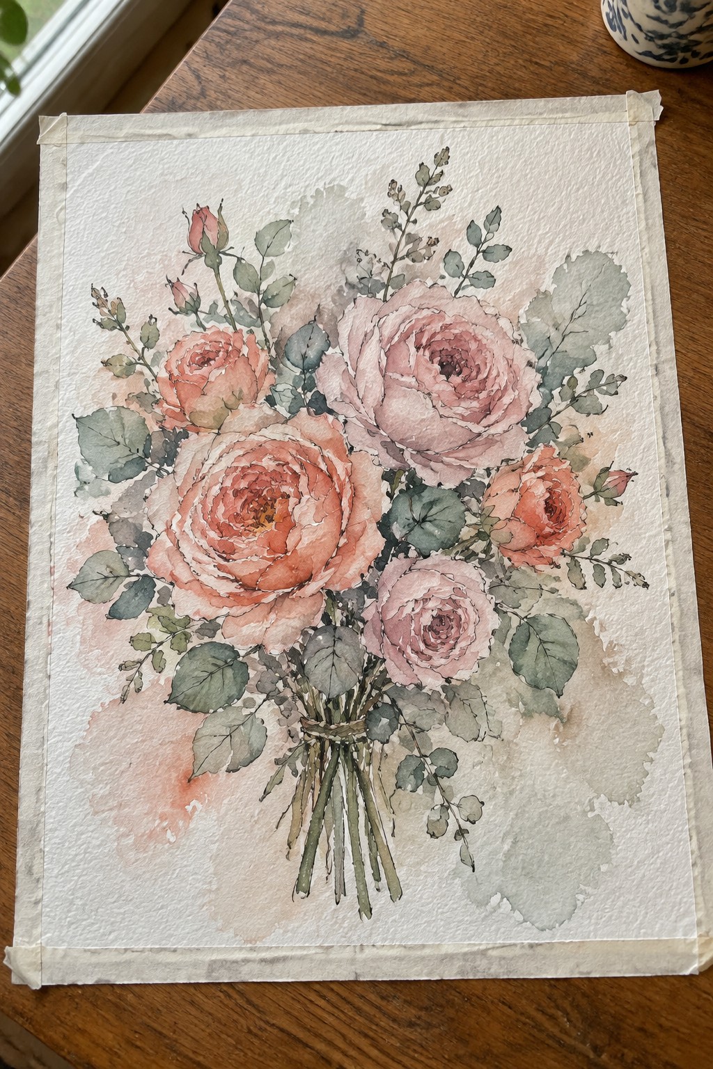 Watercolor bouquet of pink and peach roses with green leaves tied on wood surface