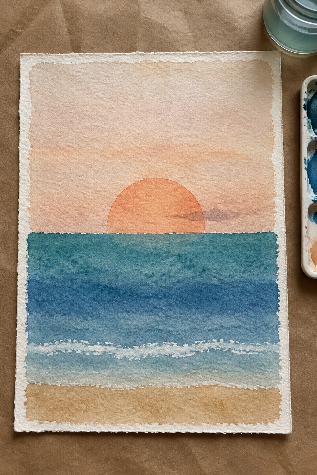 Watercolor painting of a minimalist sunset over the ocean with an orange sun half visible above blue water, soft white waves, and a tan beach strip at the bottom.