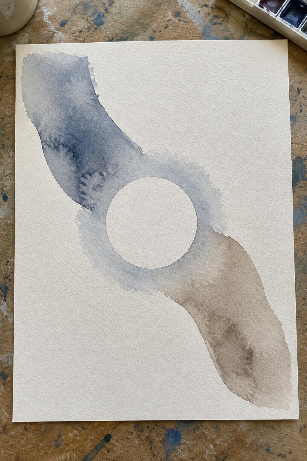 Abstract watercolor with blue-gray and brown washes framing a central white circle