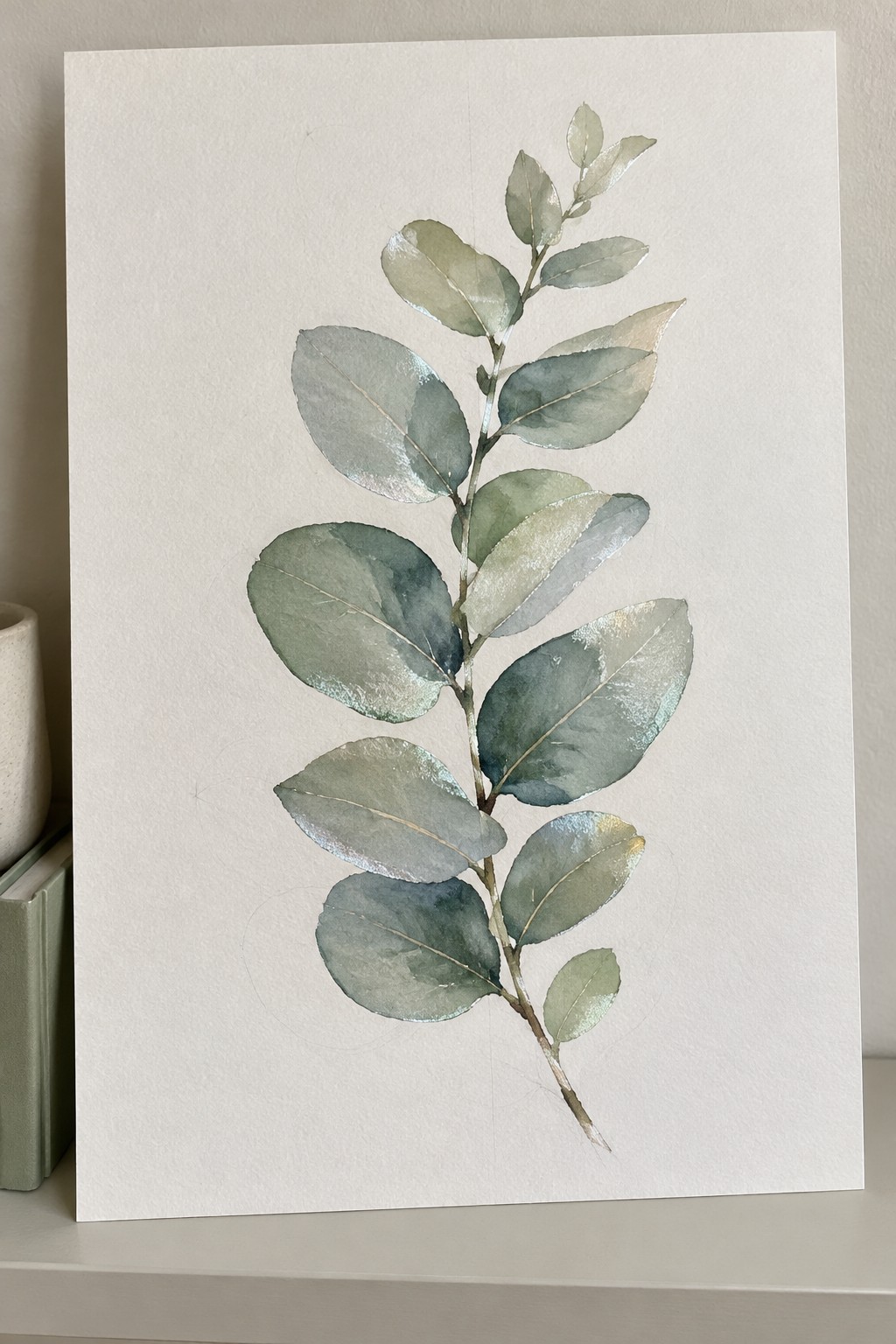 Watercolor eucalyptus branch with green leaves and gold highlights on white paper