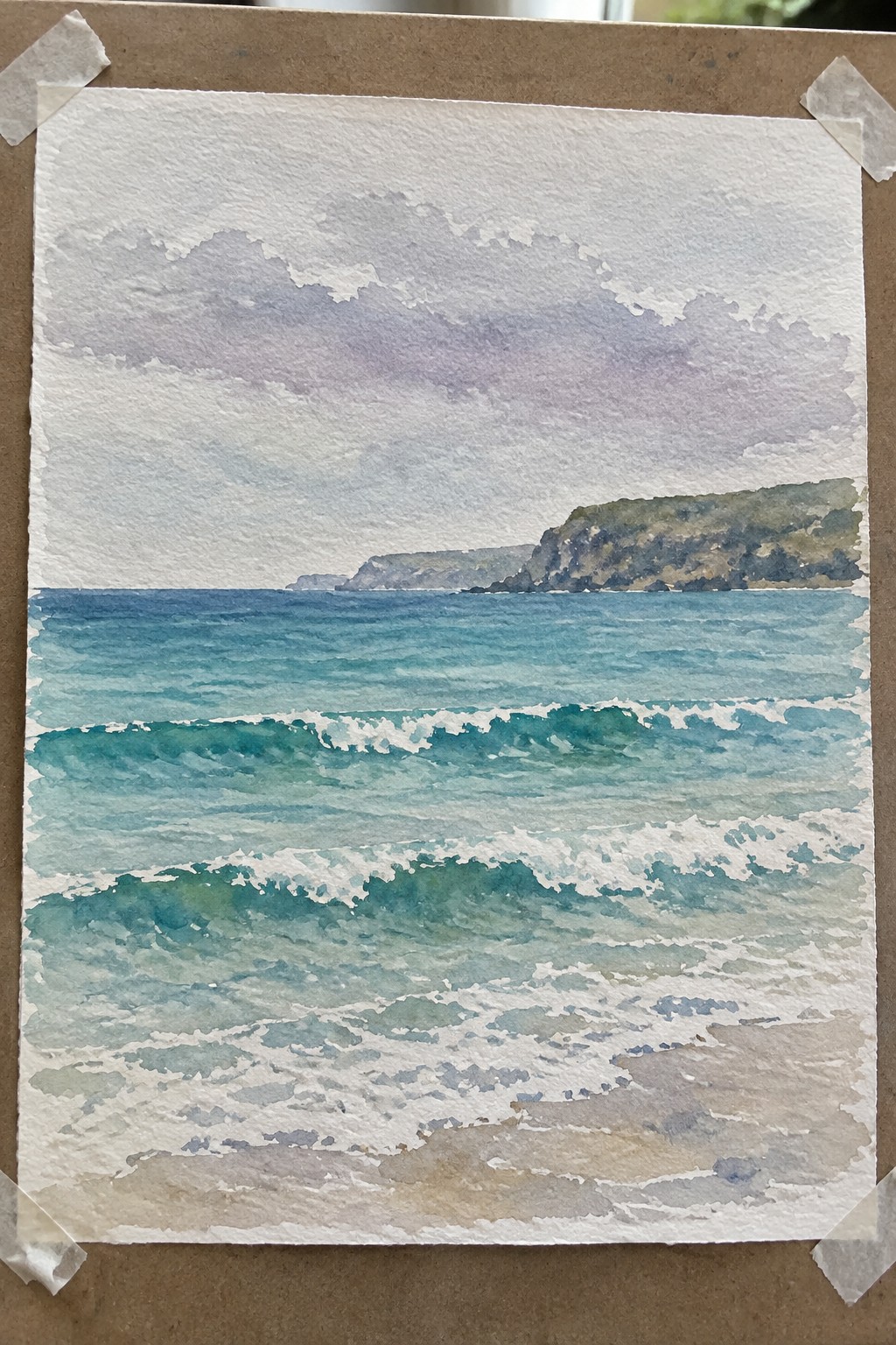 Watercolor of turquoise waves with white foam approaching sandy beach, distant cliffs under purple-gray clouds
