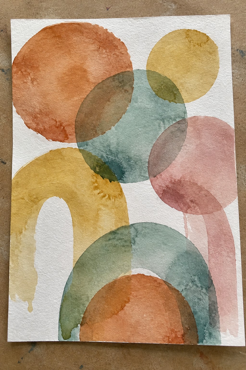 Abstract watercolor with overlapping circles and arches in orange, yellow, teal, and pink