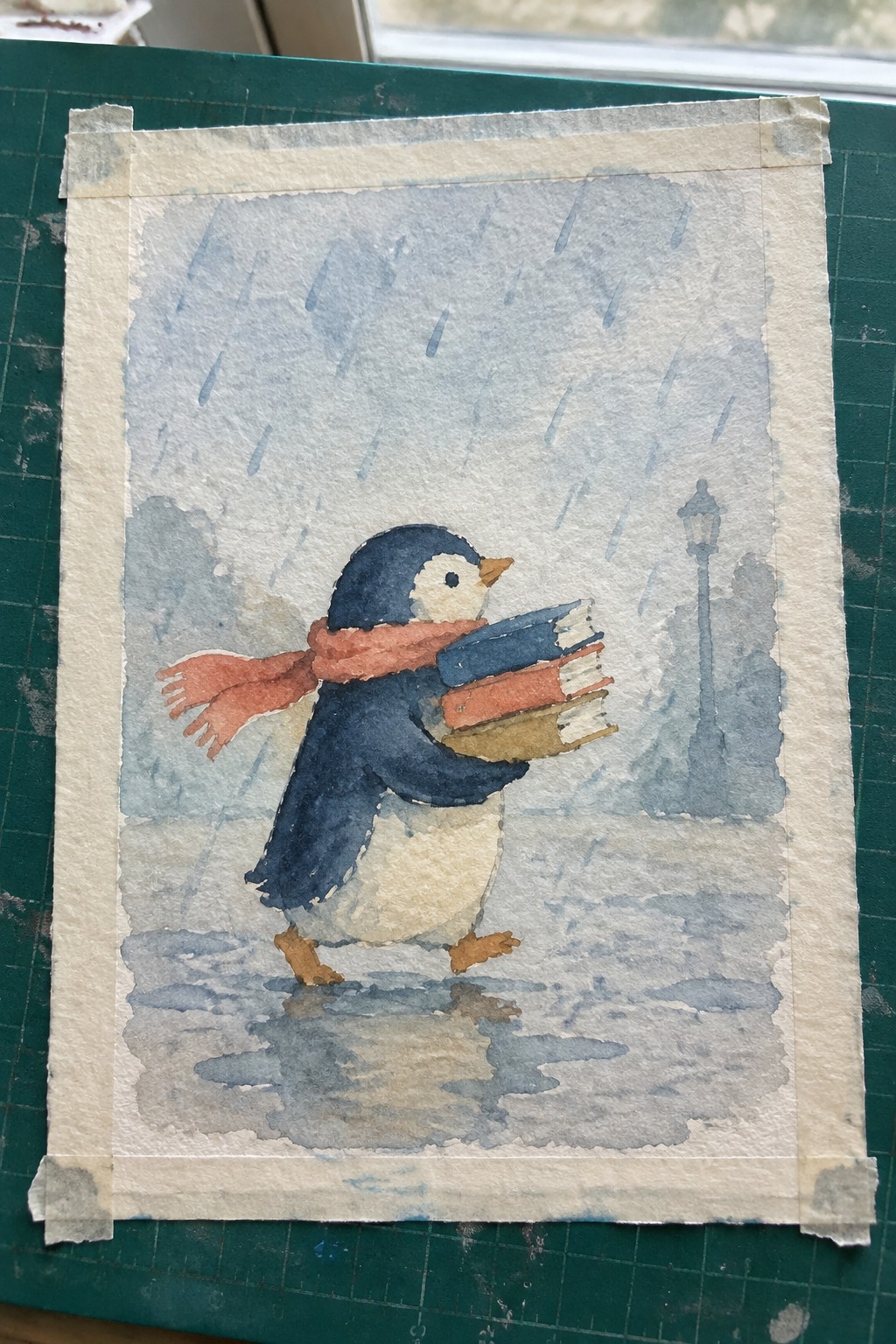 Watercolor penguin in red scarf carries books through rain on wet street with lamppost.