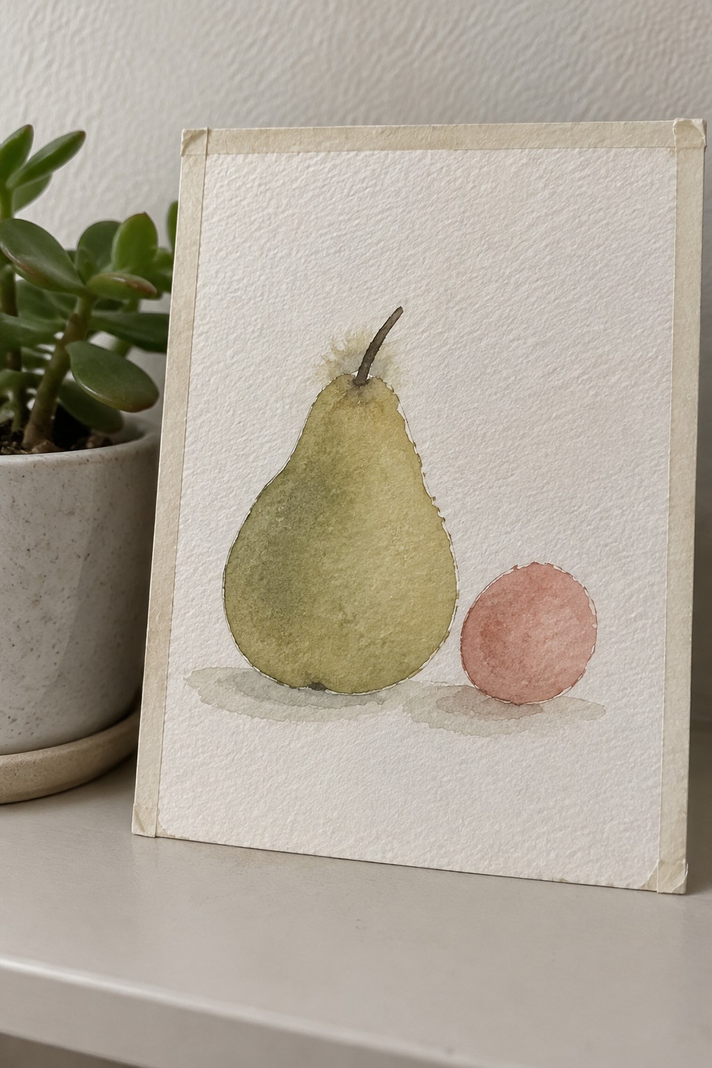Watercolor painting of a green pear next to a small pink circle on white paper with soft shadows underneath.