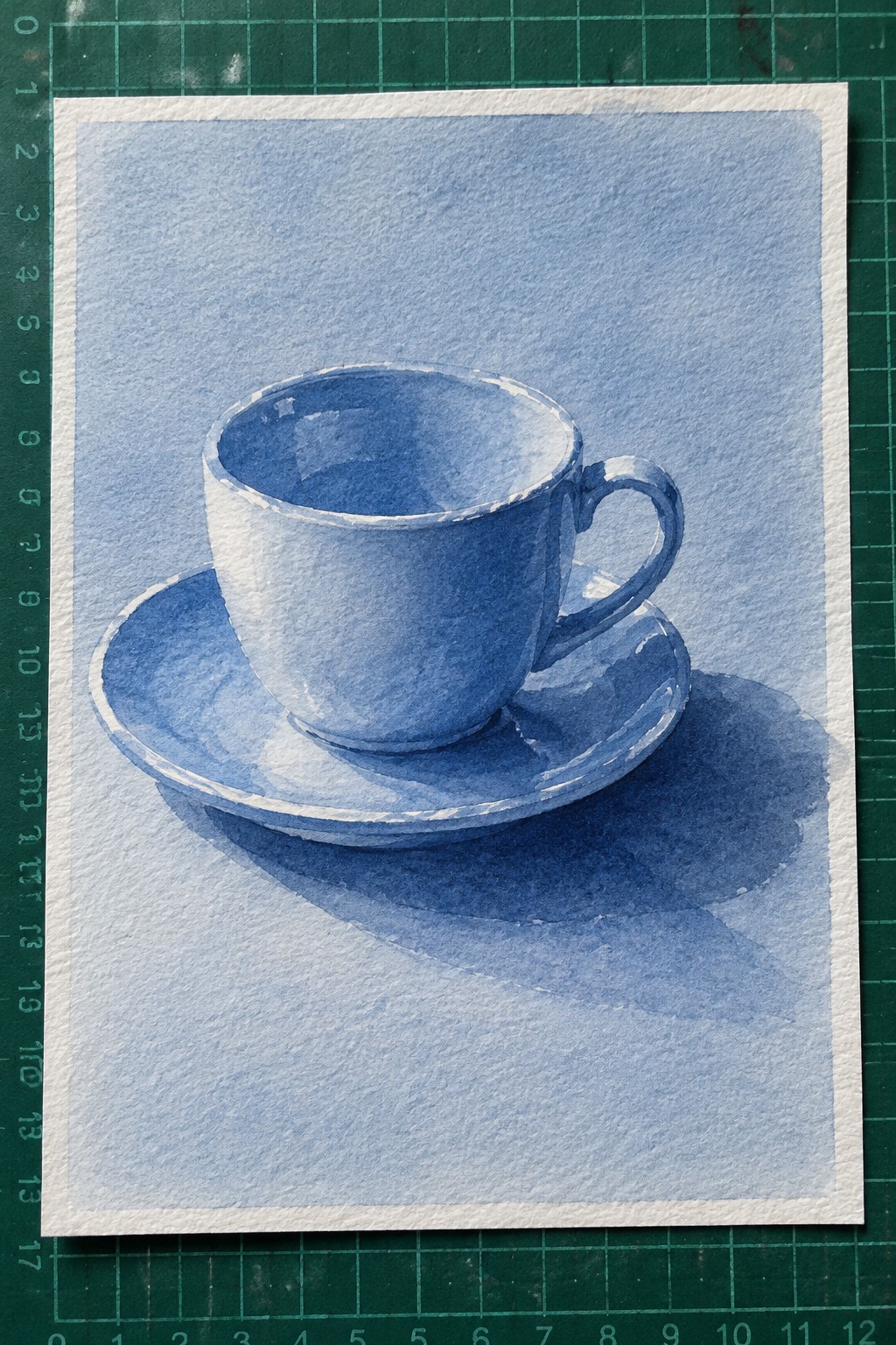 Blue watercolor painting of teacup and saucer with shadows on white paper