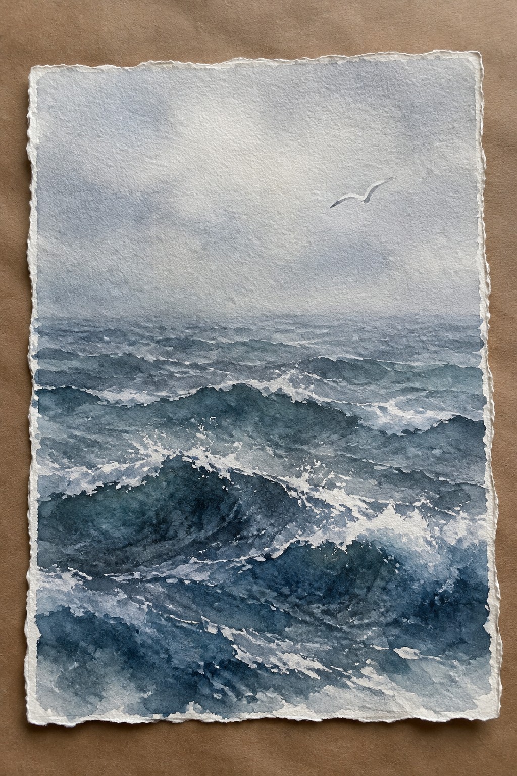 Watercolor seascape of choppy blue waves with white foam and a lone bird in gray sky