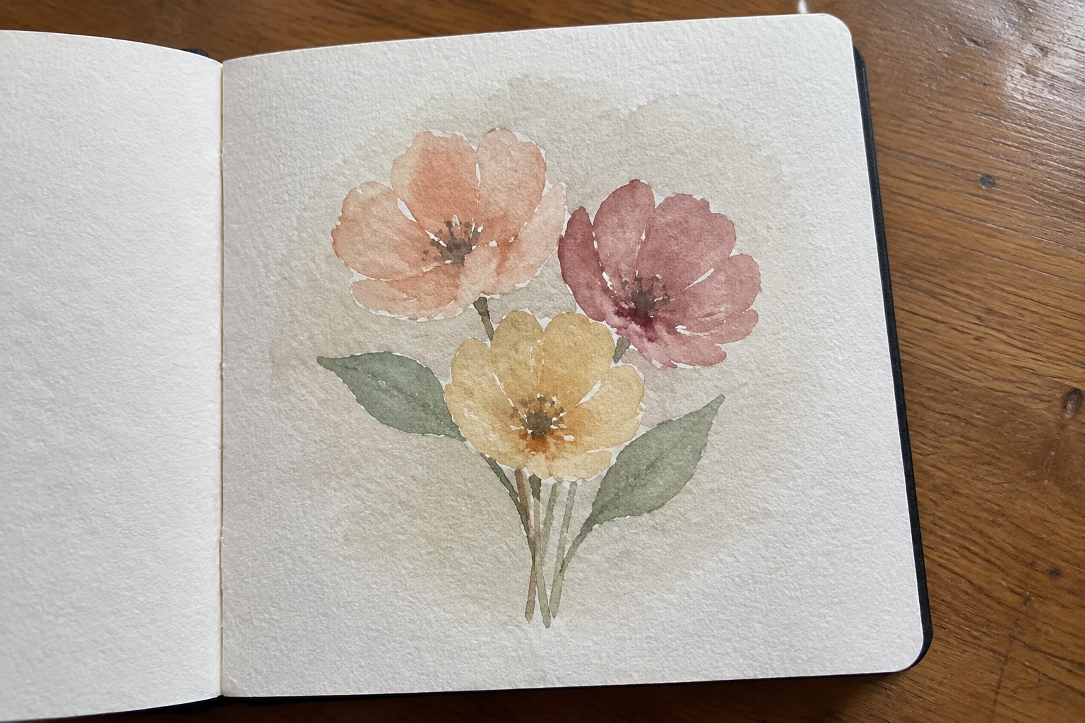 Watercolor painting of three flowers in peach, yellow and pink with leaves in sketchbook