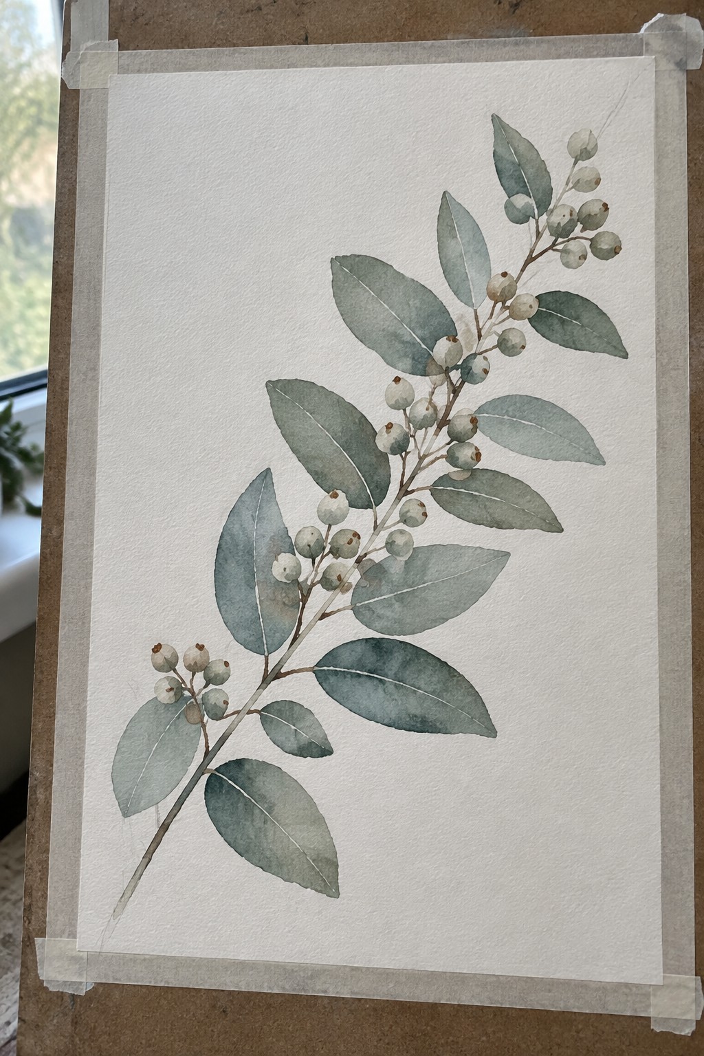 Watercolor painting of a leafy branch with small round berries on white paper taped to a surface.
