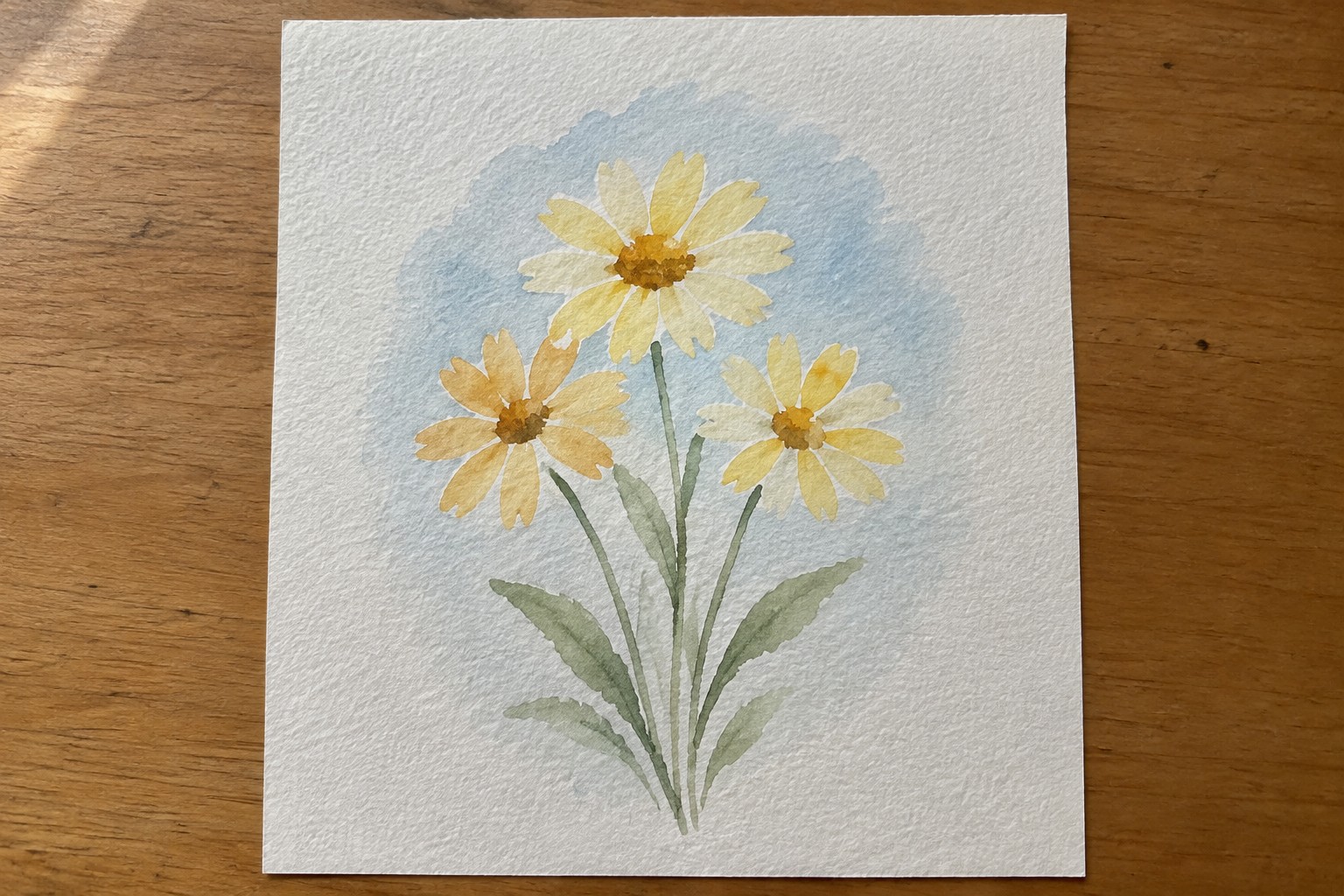 Watercolor painting of three daisies with pale yellow petals, orange centers, and green stems