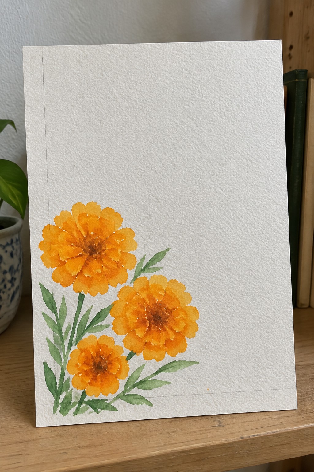 Three orange marigold flowers with green leaves in watercolor on white paper