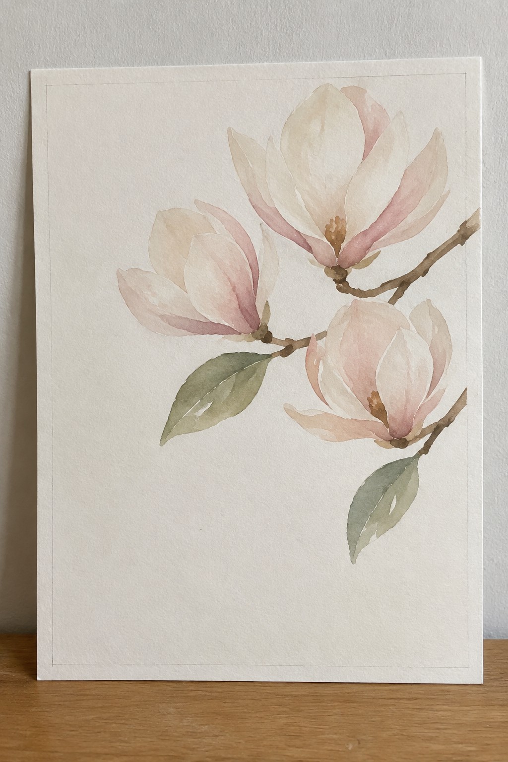 Watercolor painting of soft pink magnolia flowers on branch with green leaves