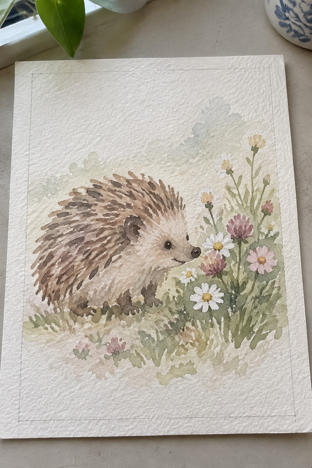 Watercolor hedgehog sniffing pink and white wildflowers in a meadow