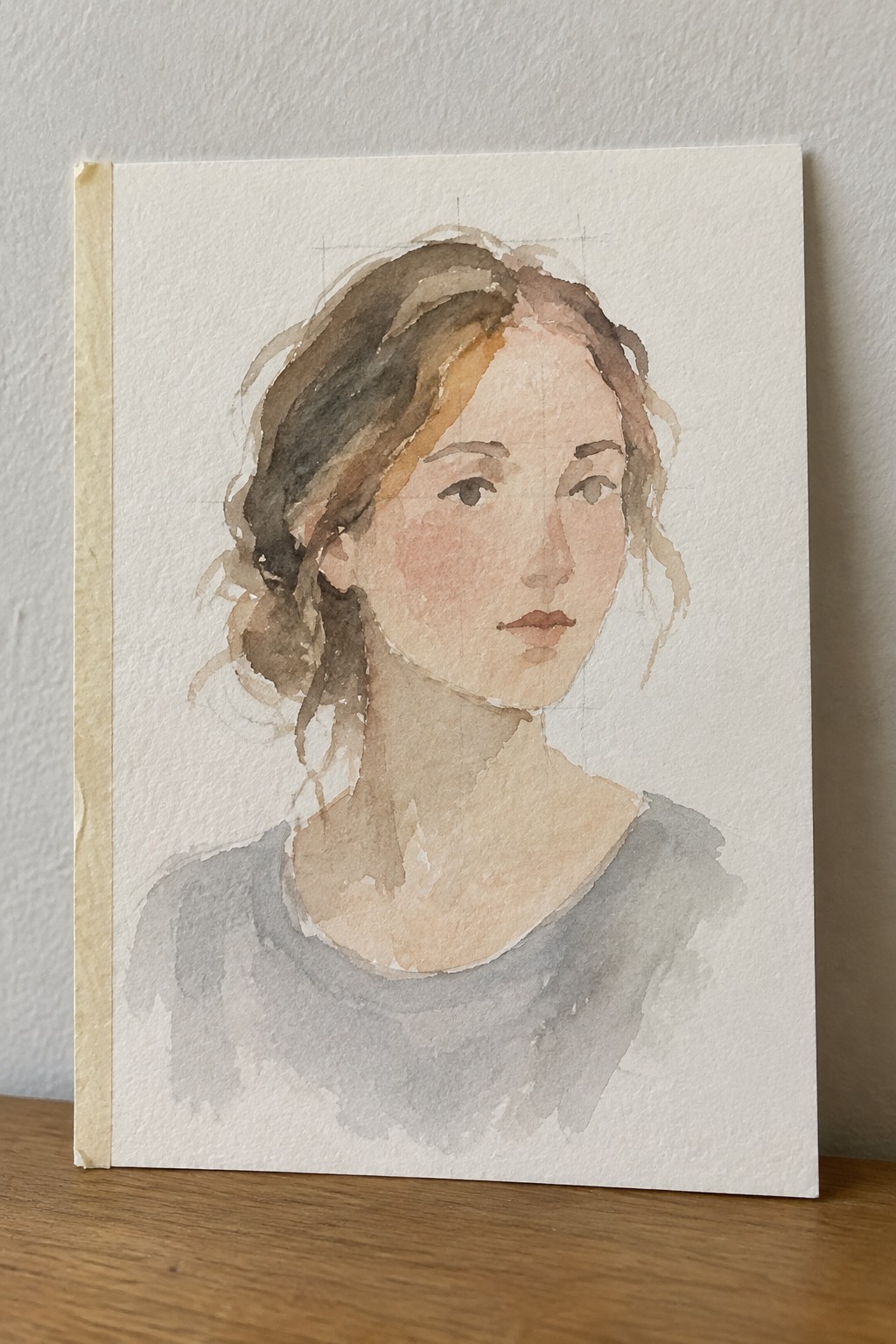 Watercolor portrait of a woman with brown hair in a gray top on paper