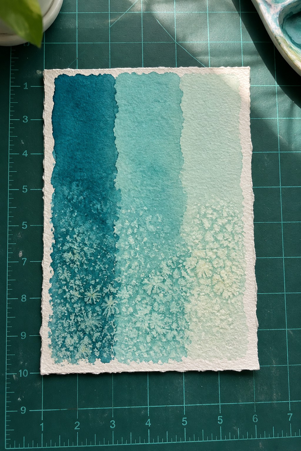 Watercolor gradient from dark teal to light green with salt crystal textures on paper
