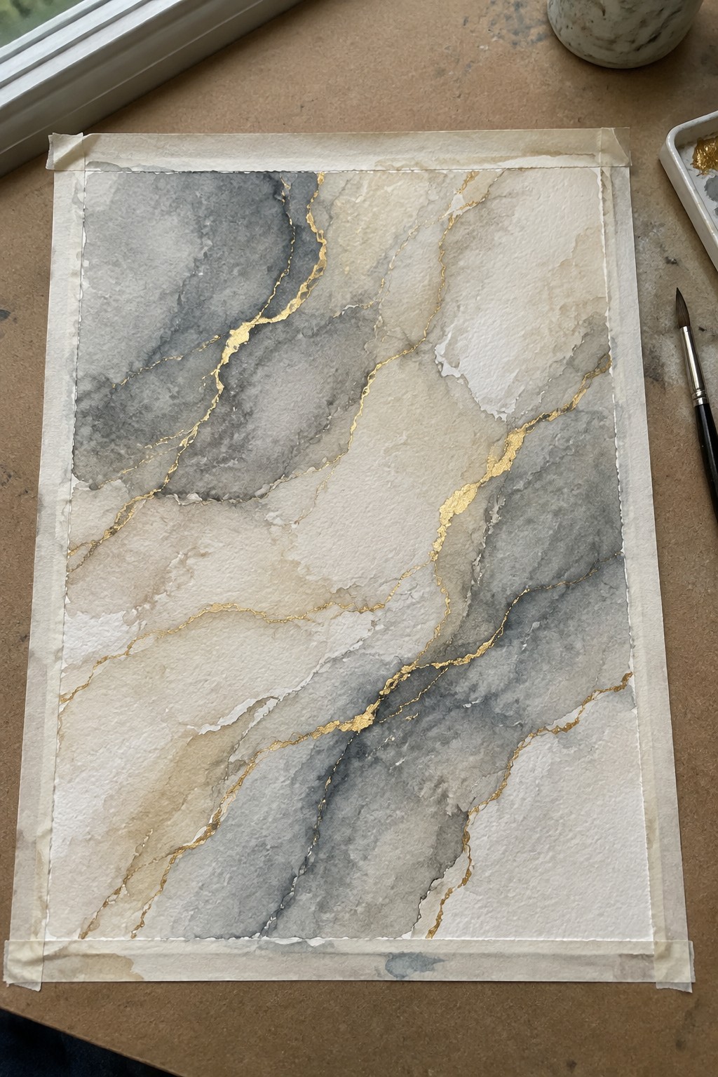 Abstract watercolor with gray tones, beige washes and gold veins on taped paper