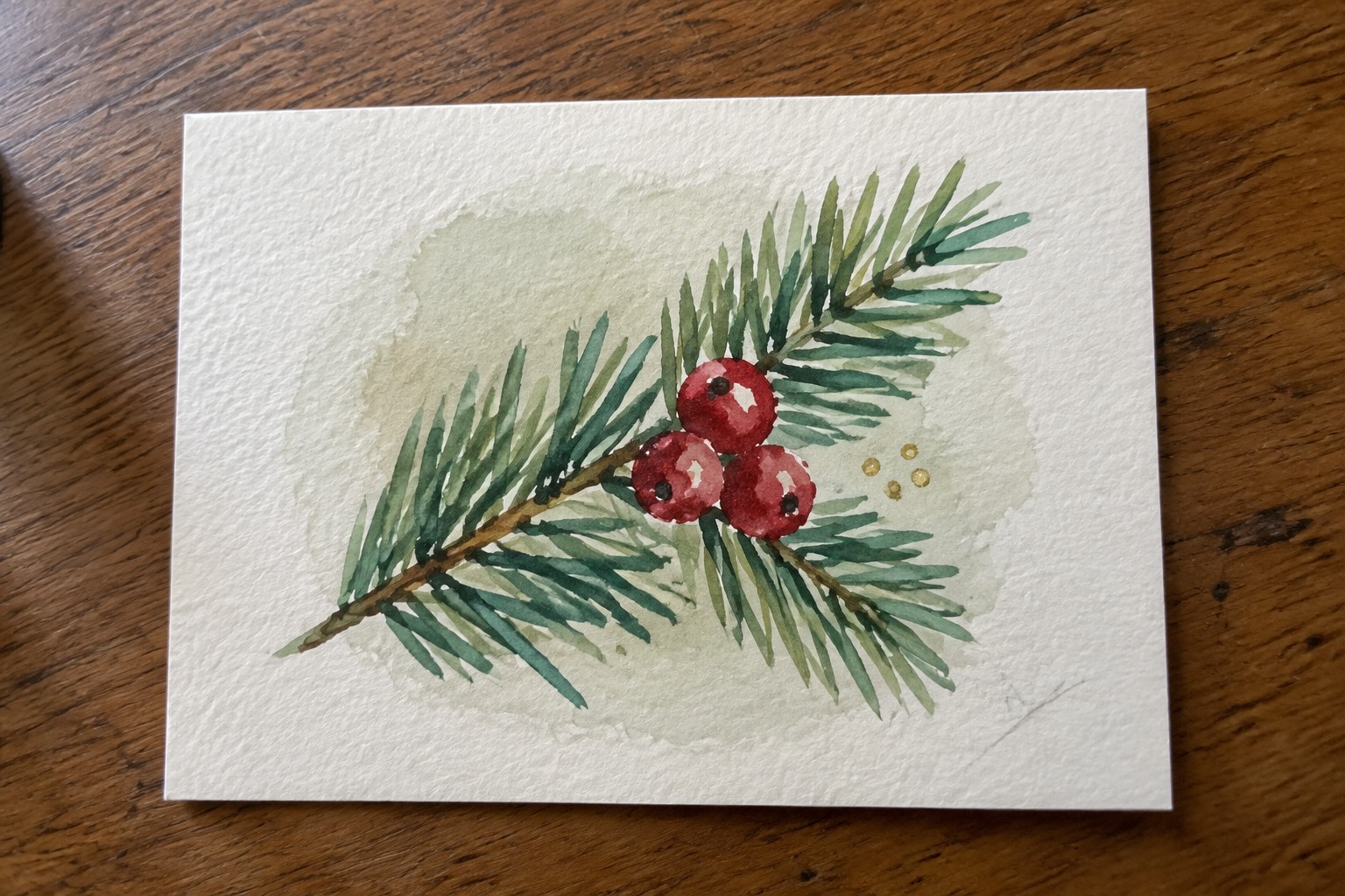 Watercolor of pine branch with three red berries on textured white paper
