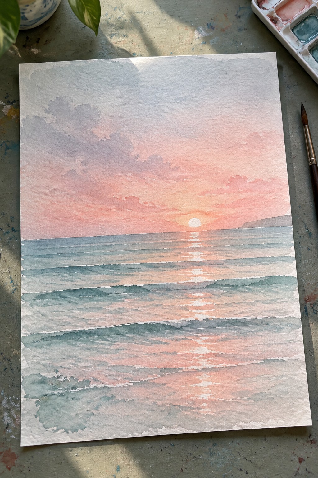 Watercolor sunset seascape with pink-orange sky, sunlit waves, palette and brush nearby