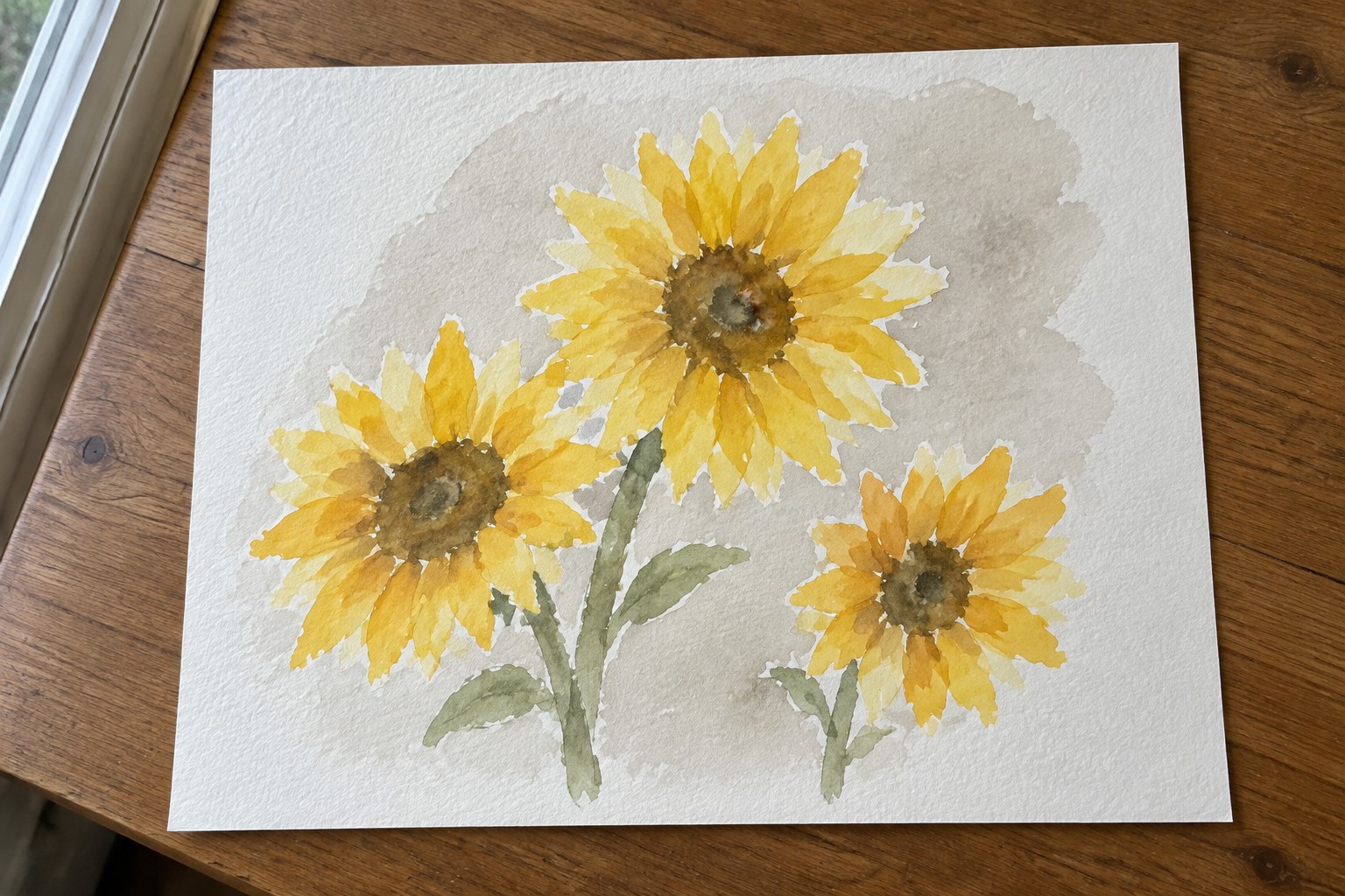 Yellow watercolor sunflowers with brown centers and green stems on wood