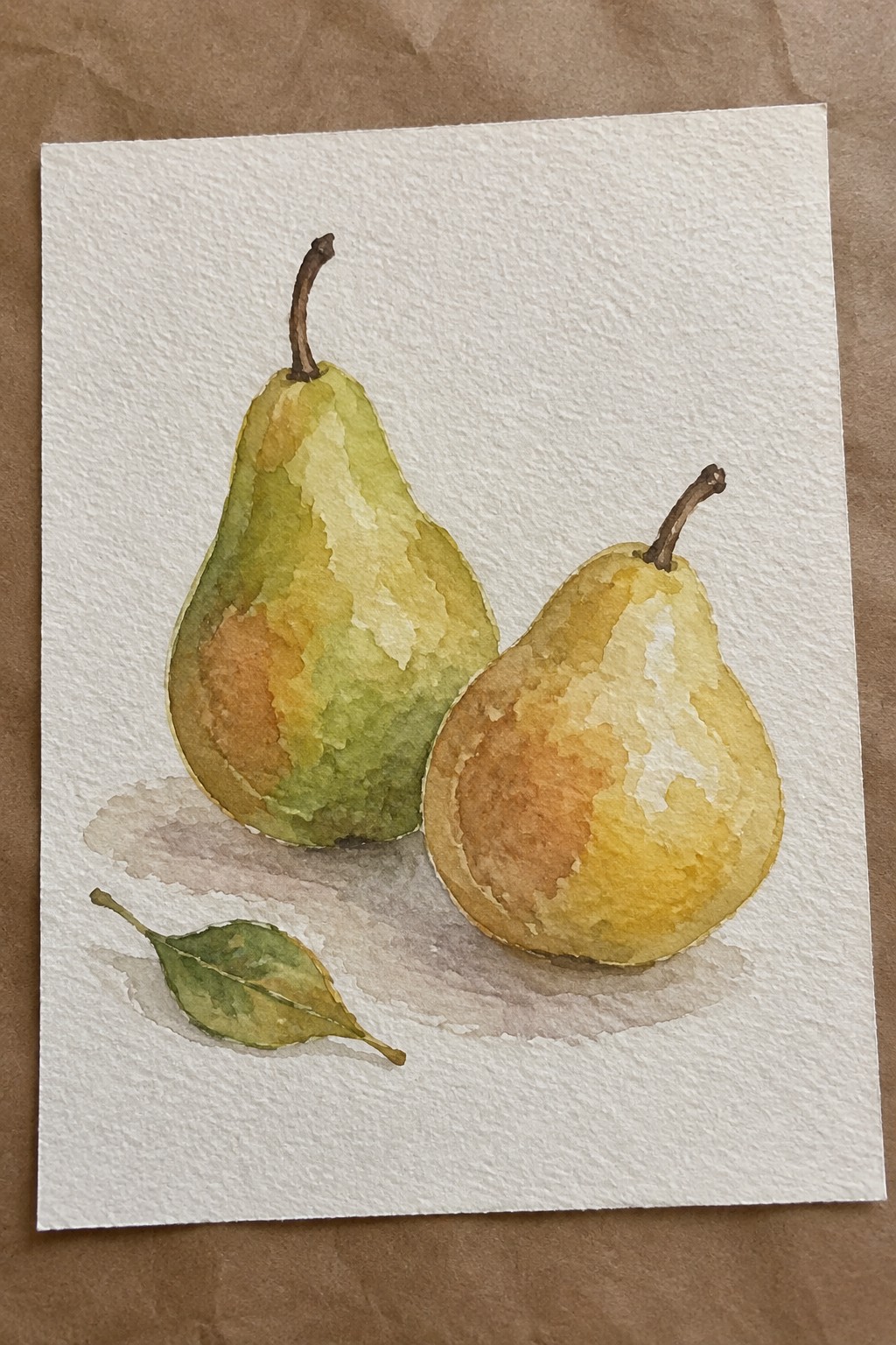 Watercolor still life of two pears in green and yellow beside a leaf.